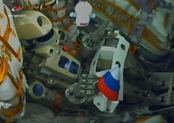 费多尔端坐在飞船中央，手中还拿着一面俄罗斯国旗。图片来源：俄罗斯航天局
