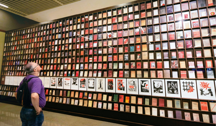 2018年5月9日，一位外国观众被北京“真理的力量——纪念马克思诞辰200周年主题展览”中一面展示不同国家出版的500多种《共产党宣言》的书墙所吸引。中新社记者 贾天勇/摄