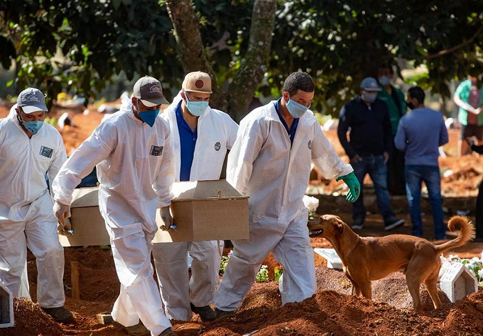 Cemetery workers in protective clothing carry a coffin (AAP)
